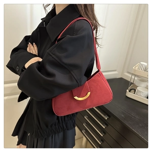Close-up of deep red suede baguette bag with vintage gold magnetic hardware and sleek texture