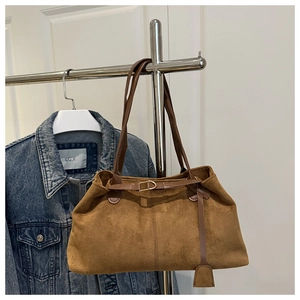 Détail d'un sac cabas en daim marron montrant la texture et les fines lanières