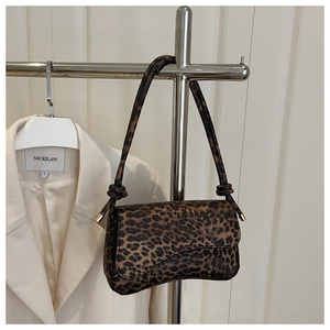 Detail view of leopard print shoulder bag with knotted strap on a display hanger