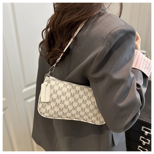 Detail of monogram shoulder bag featuring metal zipper and fashion tag on gray blazer