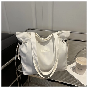 Detail of white nylon tote bag featuring black FASHION label and side drawstring detail
