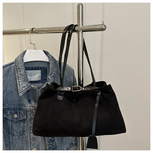 Détail d'un cabas vintage en daim noir avec boucle dorée et lanière de cuir décorative