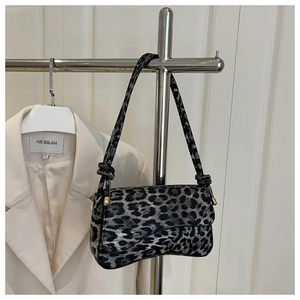 Detail of leopard print underarm bag with wavy base hanging on a boutique rack