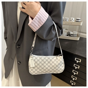 Close-up of retro underarm bag with M-letter print and fashion tag on grey suit