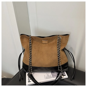 Detail of retro brown suede and black leather tote bag with gold buckle on chair