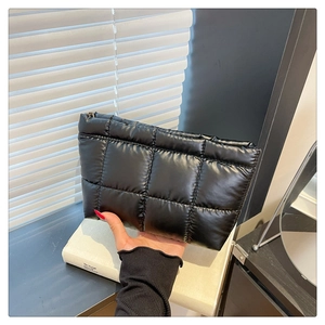 Gros plan sur la trousse de maquillage noire matelassée avec finition brillante et fermeture éclair
