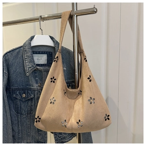Macro detail of beige suede tote bag with intricate laser-cut floral hollow patterns