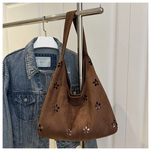 Detail of brown suede tote bag with laser-cut floral patterns and wide shoulder strap
