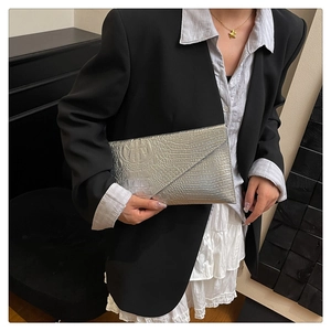 Detail of silver crocodile-embossed envelope clutch bag with glossy metallic finish