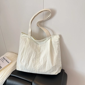 Minimalist cream tote bag with crinkled nylon texture and wide shoulder strap