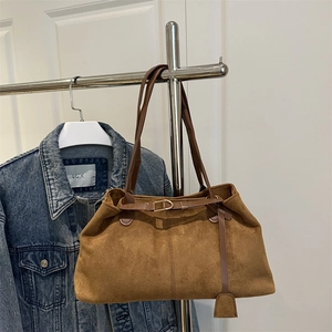 Sac cabas vintage en daim marron avec lanières en cuir à côté d'une veste en jean