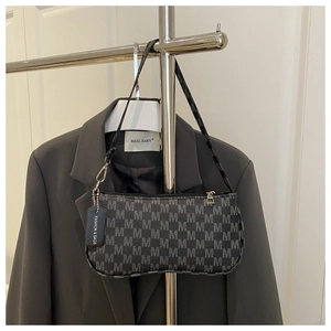 Detail of vintage gray baguette bag with M-pattern print hanging on a suit