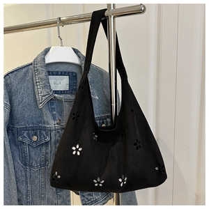 Detail of black laser-cut floral patterns on a large suede shoulder tote bag