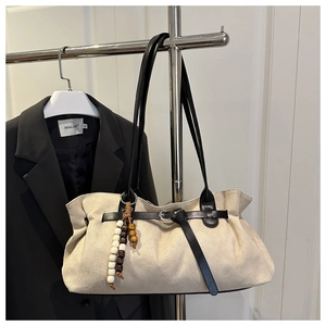 Detail of off-white suede tote bag featuring wooden beads and black leather straps
