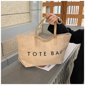 Detail of earthy suede large tote bag with TOTE BAG lettering and soft texture finish