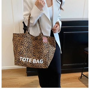 Detailed close-up of large leopard print tote bag featuring TOTE BAG text and dual handles