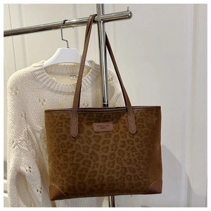 Macro detail of leopard print suede tote bag with brown leather handles and brand tag