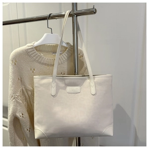 Detail of a creamy white faux suede tote bag with reinforced corners and leather brand patch