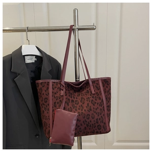 Dettaglio della borsa tote leopardata bordeaux con portamonete coordinato su un appendino