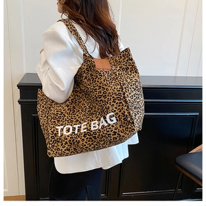Detailed view of leopard print canvas tote bag with white TOTE BAG lettering and brown leather patch
