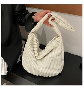 Detail of cream corduroy shoulder bag showing knot strap design and golden metal zipper