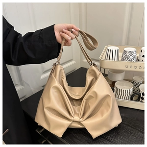 Detail of beige textured faux leather shoulder bag with a large decorative bow