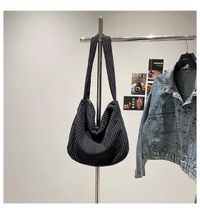 Detail of black corduroy hobo bag showing ribbed texture and shoulder strap on hanger