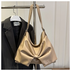 Dettaglio della borsa hobo beige con grande fiocco decorativo e trama in ecopelle liscia