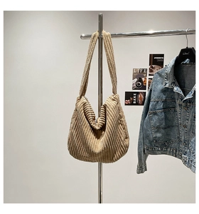 Detail of beige corduroy hobo bag showing thick ribbed texture and wide shoulder strap