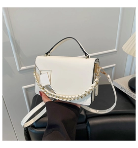 Close-up of a white leather handbag featuring a golden metal buckle and chain handle