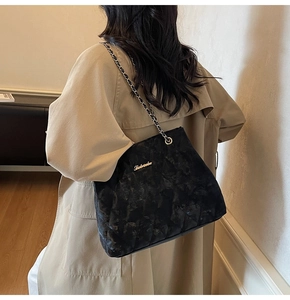 Détail du sac bandoulière noir matelassé avec chaîne dorée et logo en métal chic