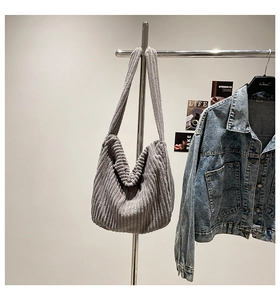 Detail of grey corduroy hobo bag texture hanging with denim jacket in minimalist setting