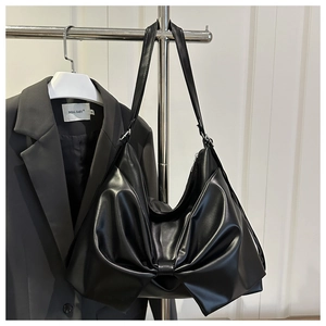 Dettaglio di una borsa tote in pelle nera con fiocco decorativo e cerniera in metallo