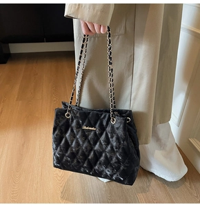 Détail du sac fourre-tout noir matelassé avec chaînes dorées et logo en métal doré