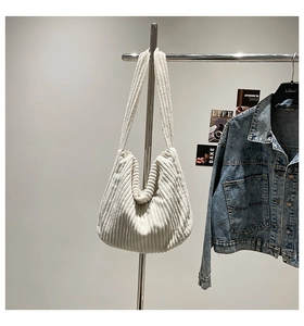 Detailed texture of white corduroy fabric on a minimalist large hobo shoulder bag
