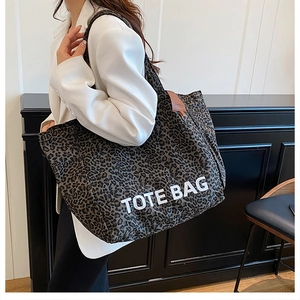 Close-up of leopard print tote bag featuring TOTE BAG text and brown leather trim