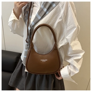 Macro view of brown leather crescent bag detailing the fashion logo and silver metal hardware