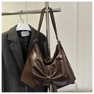 Dettaglio del grande fiocco decorativo sulla borsa tote in ecopelle marrone scuro