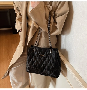 Détail du sac fourre-tout en velours noir matelassé avec bandoulière chaîne dorée