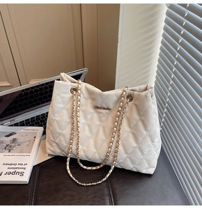 Detail of quilted diamond pattern and leather chain strap on a chic shoulder bag
