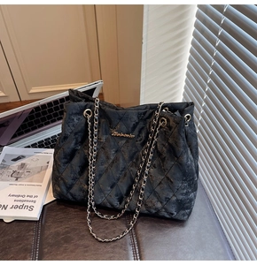 Detail of black quilted tote bag with gold chain strap and metallic finish on leather