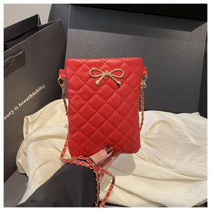 Détail du mini sac bandoulière matelassé rouge avec nœud doré et bandoulière chaîne