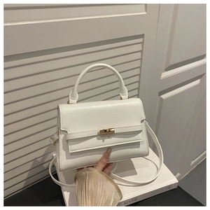 Detailed shot of white PU leather handbag featuring a gold turn-lock closure on white tray