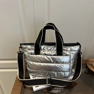 Borsa tote trapuntata argento metallizzato con tracolla nera su una rivista sul tavolo