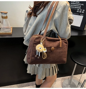 Detailed view of brown suede tote bag with fur ball charm and vintage metal buckle