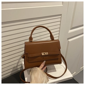 Detail of caramel leather handbag with gold metallic twist lock and top handle