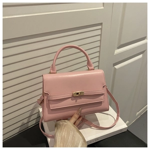 Detail view of pink leather handbag with gold twist lock and adjustable shoulder strap