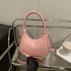 Pink crescent handbag on metallic stand with adjustable shoulder strap and silver text