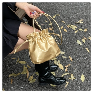 Detail of champagne gold drawstring bucket cosmetic bag with smooth leather texture