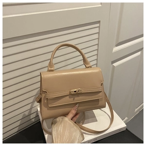Detail view of the beige top handle bag with a gold twist-lock and textured flap